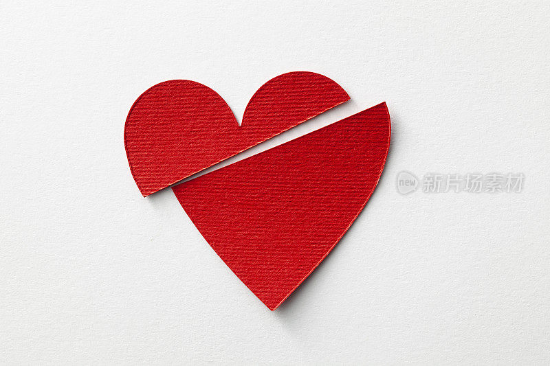破碎的心。红色剪纸心在白色的背景。