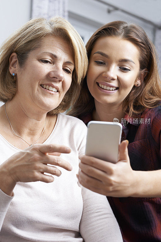 十几岁的女儿向母亲展示如何使用手机