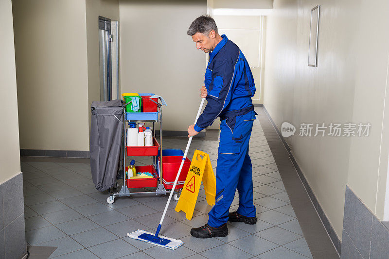 男工人用扫帚清扫走廊