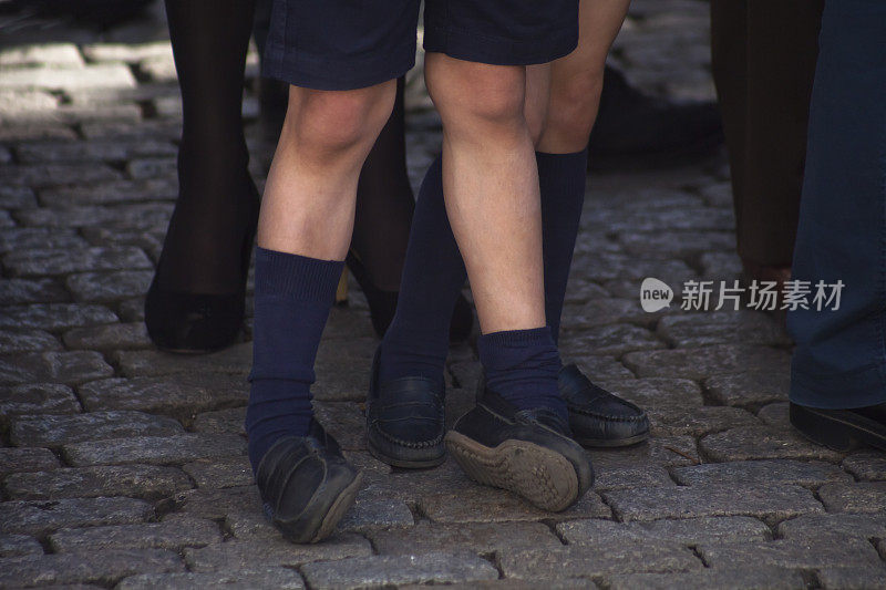 在鹅卵石铺成的街道上穿着短裤的男孩的细节。