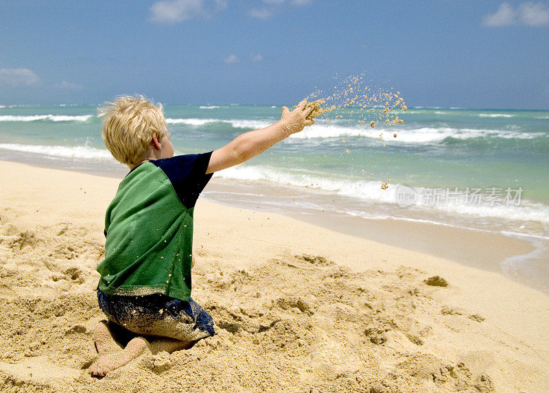 小男孩在沙滩上玩，扔沙子