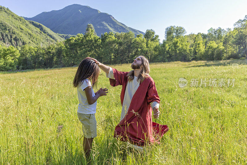 耶稣基督和一个孩子在田野里祈祷