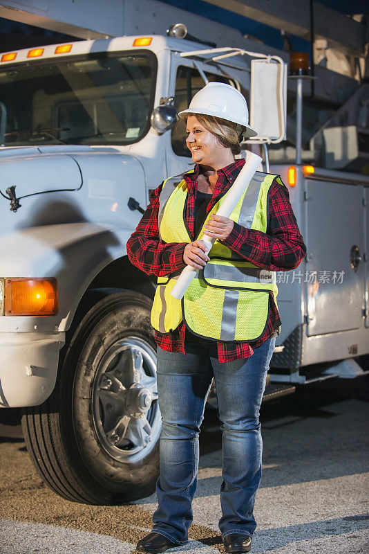 女工人穿着安全背心和安全帽与卡车