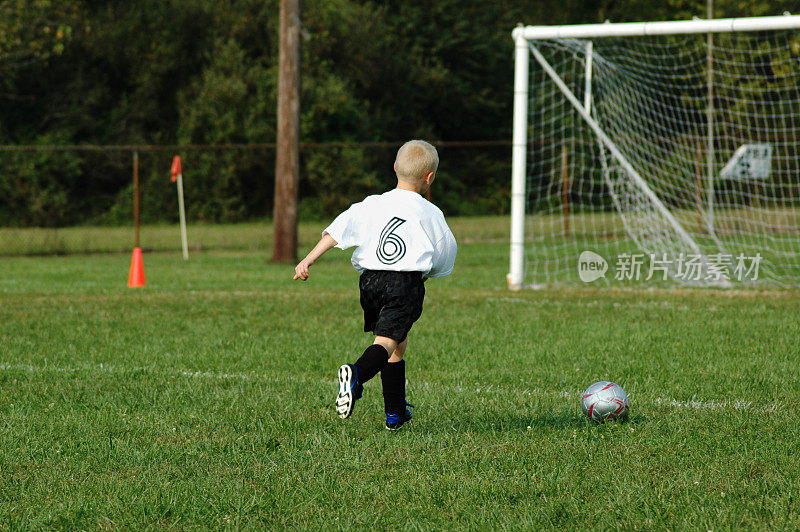 年轻的足球运动员冲向球门