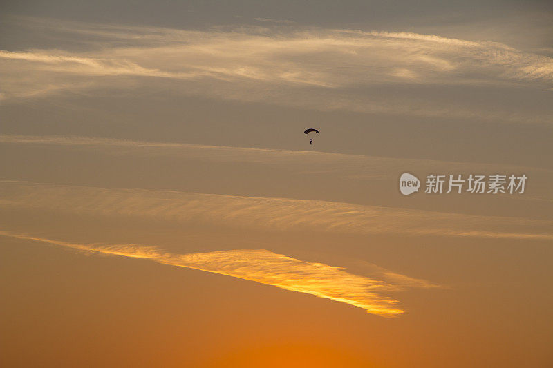 美丽的夕阳下跳伞者的剪影