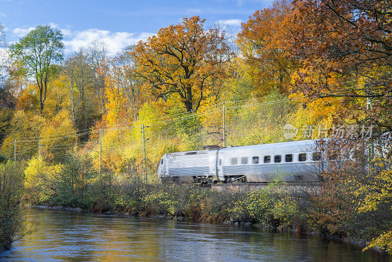 一列瑞典火车在秋天的风景中驶过河流