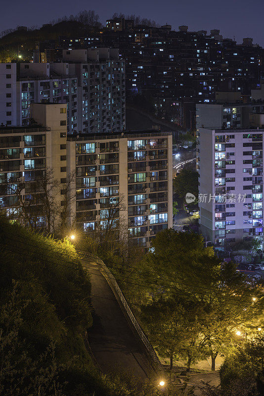 夜晚城市的灯光照亮了公寓的窗户，照亮了高层住宅