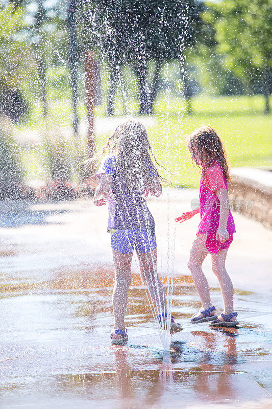 两个小女孩在水花公园的喷泉里玩耍
