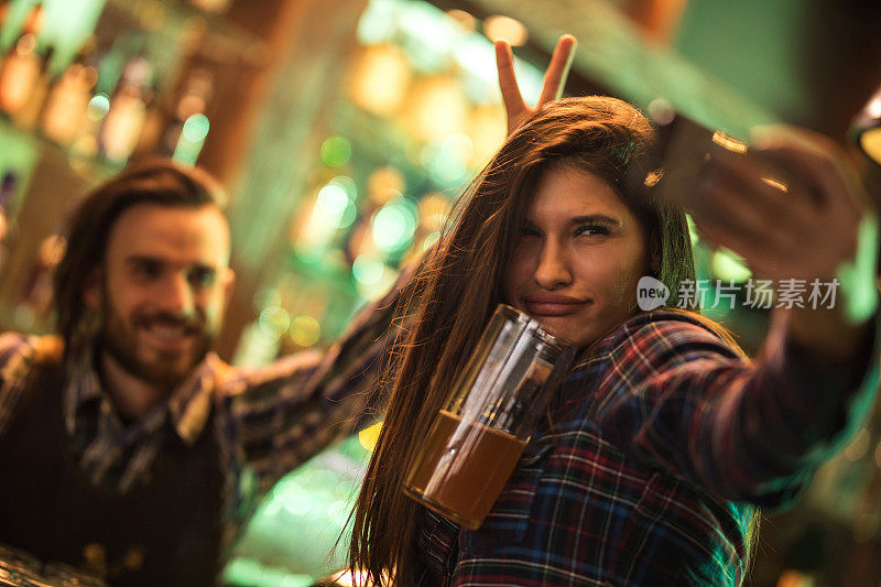 一个年轻女子在酒吧和酒保自拍。