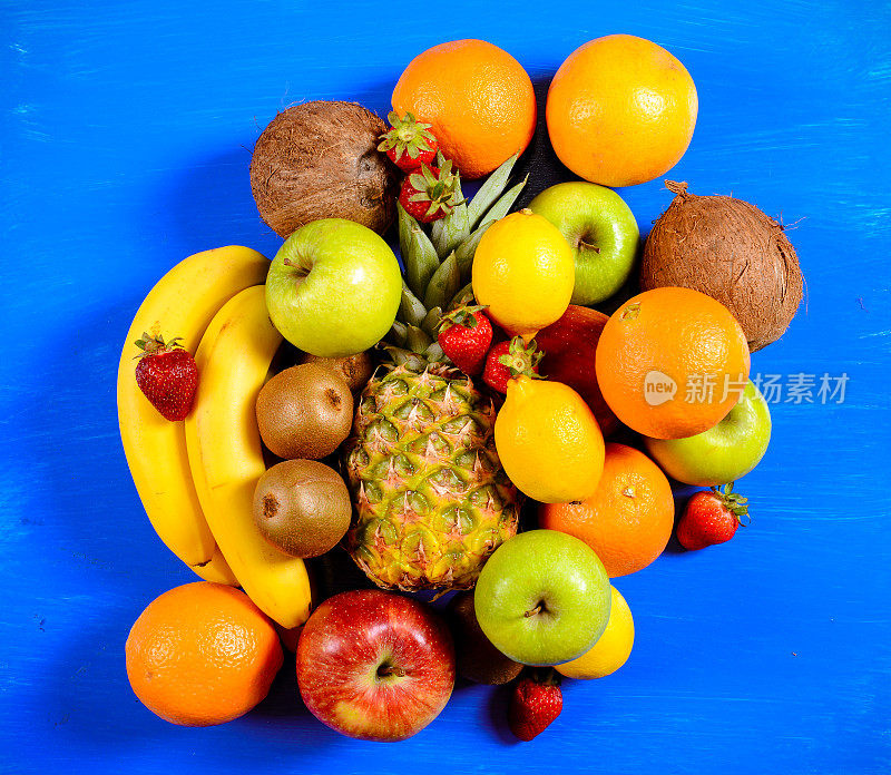 菠萝、葡萄柚、草莓、猕猴桃、橙子、香蕉、苹果放在蓝木板上