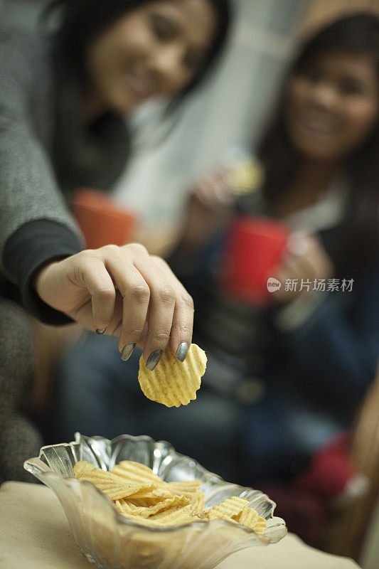 快乐的多种族女性朋友享受着咖啡和零食。