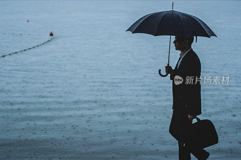 帅气的男人穿着西装，在雨中撑着伞