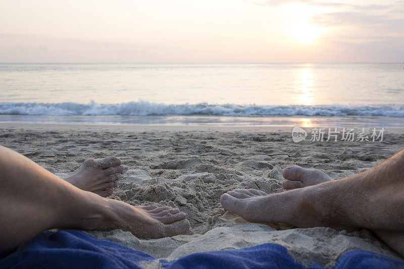 情侣们的脚在白沙滩上放松，日出