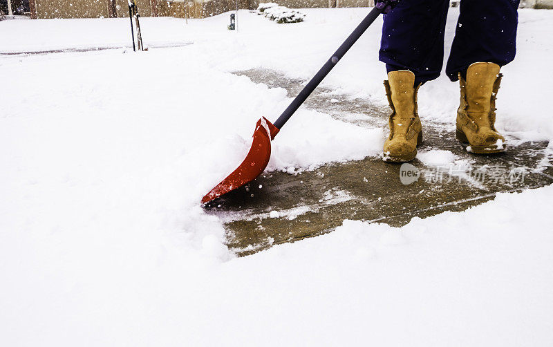 在暴风雪中从车道上铲雪的人