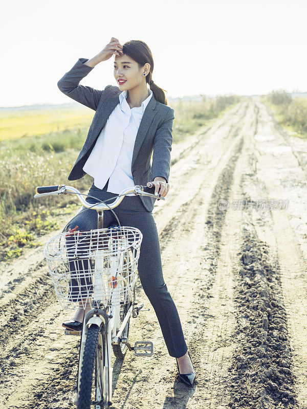 一个年轻的女商人坐在乡下的bicyale上的肖像