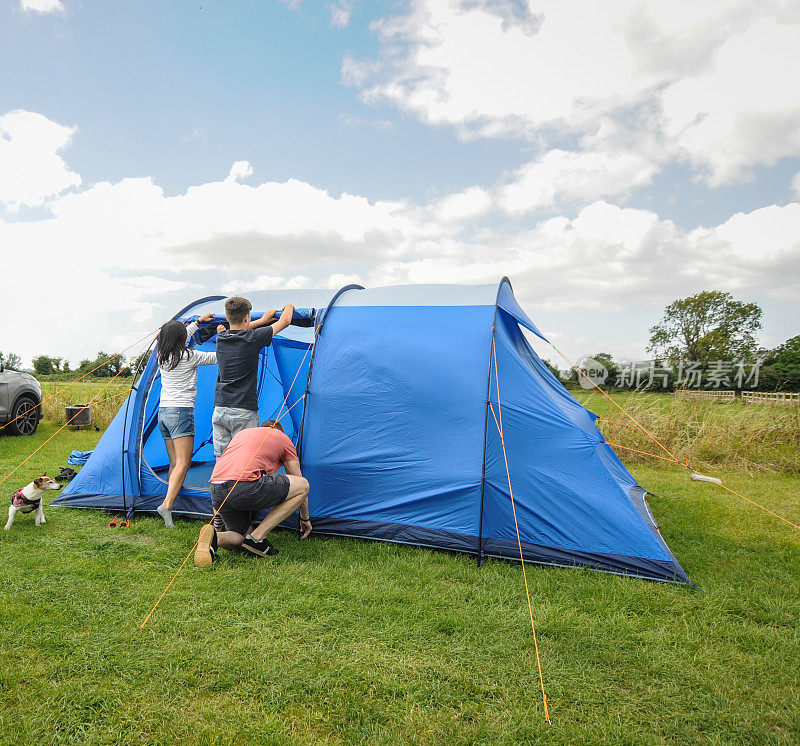 英国萨默塞特切达的一个阴天里，一家人带着狗在营地搭帐篷