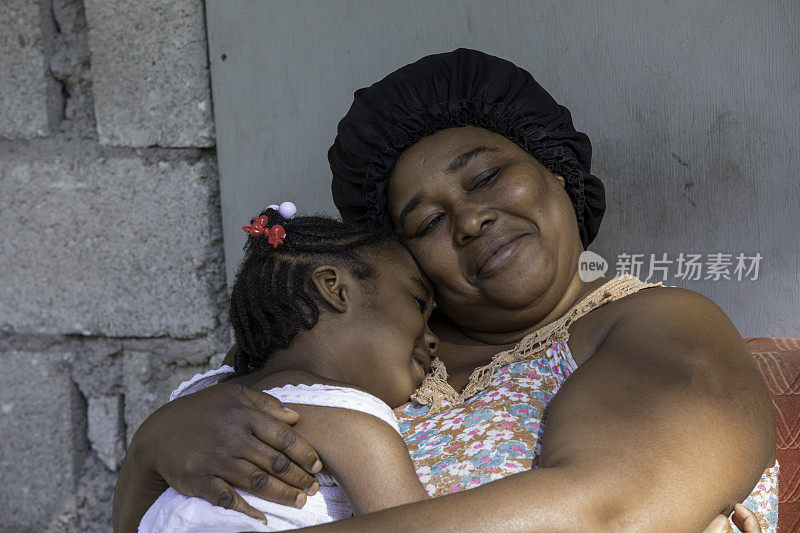 来自偏远村庄的牙买加母亲抱着她的小女儿安慰她