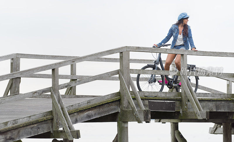 女自行车手倚靠在木桥的栏杆上