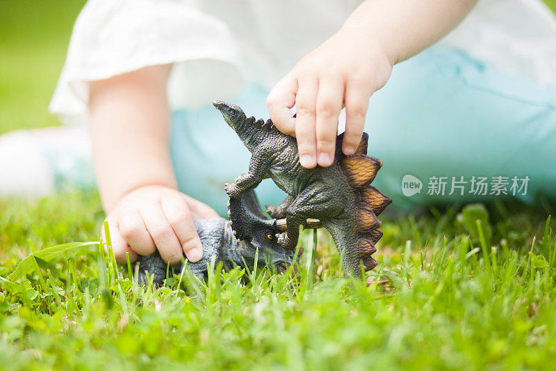 蹒跚学步的孩子在玩玩具恐龙