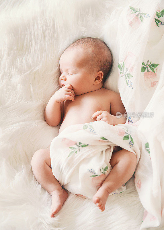 睡在白色毯子里的新生婴儿。