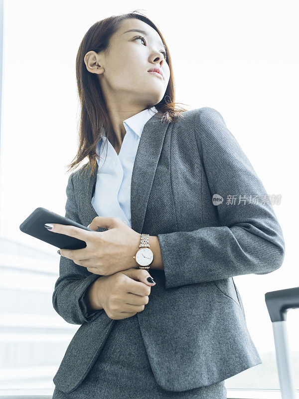 女人站在窗口使用智能手机