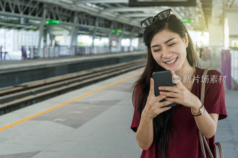 亚洲女性乘客与休闲服装通过智能手机使用社交网络在BTS轻轨或捷运地铁在大城市旅行，生活方式和交通理念