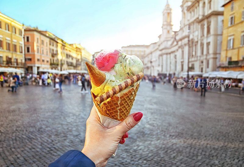 在纳沃纳广场背景下，手里拿着的意大利蛋筒冰淇淋