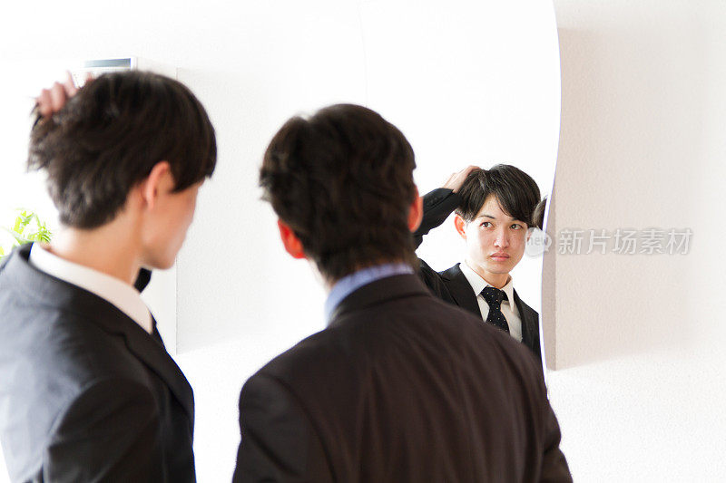 日本年轻的商人在镜子和朋友修理