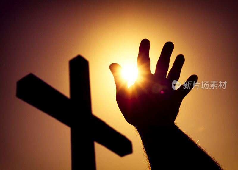 剪影十字和人的手与太阳