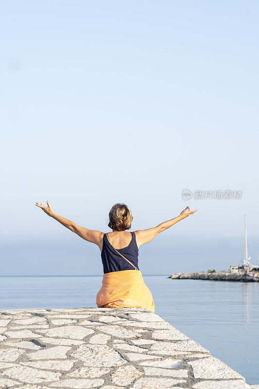 老年妇女在海边享受清晨时光