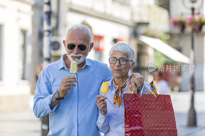 一对英俊的老夫妇在市中心散步，吃着冰淇淋