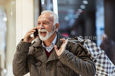 购物时间。拿着购物袋的现代老人正在打电话。消费主义、购物、生活理念