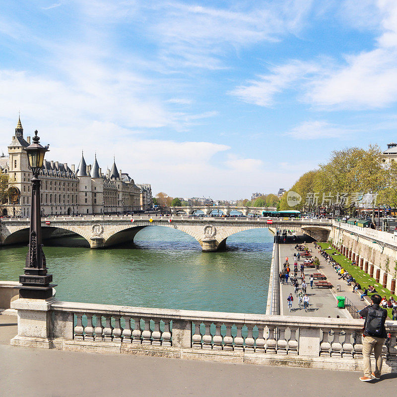 巴黎的城市景观和横跨塞纳河的圣米歇尔大桥。一名游客在阳光明媚的日子里，与人们一起拍摄美丽的海滨长廊