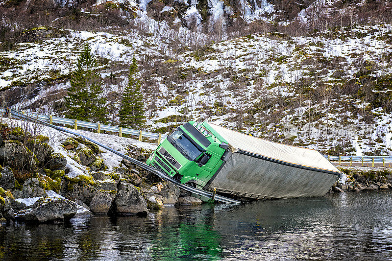 挪威北部发生事故后，一辆卡车在峡湾公路旁坠毁