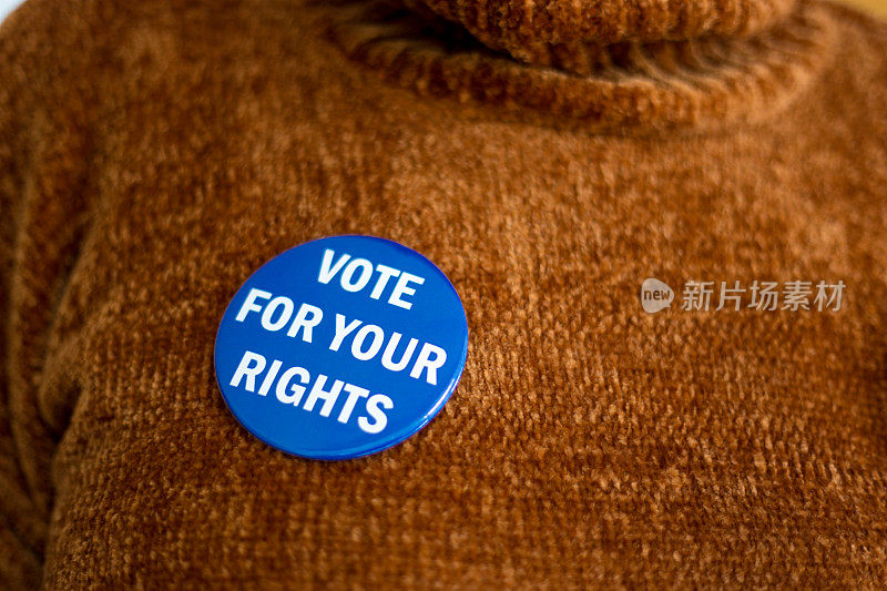 橙色毛衣上的“为你的权利投票”按钮，特写