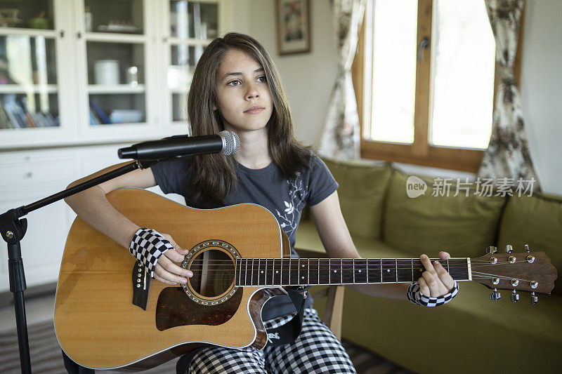一个女孩在家里弹吉他和唱歌的特写