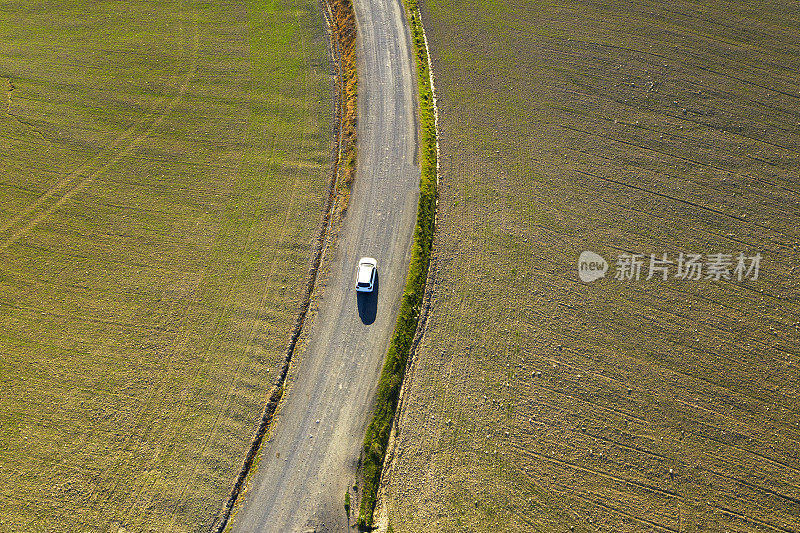 汽车在耕地之间的乡村道路上的鸟瞰图