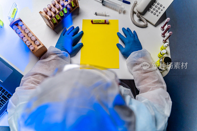 实验室科学家坐在桌子上拿着血液样本病毒试管俯视图