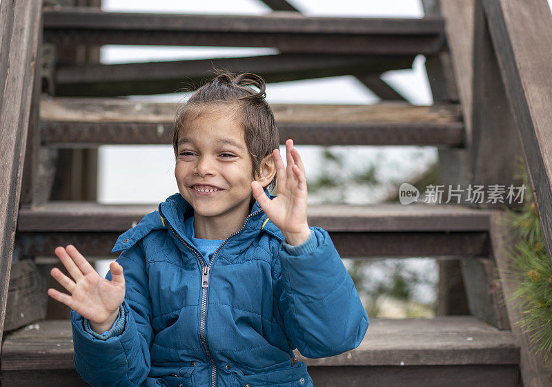 快乐的小男孩坐在木楼梯上