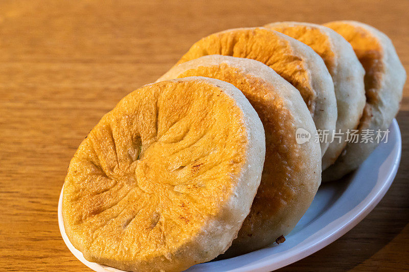 桌上有中国食物:小圆面包，馅饼。韭菜饼