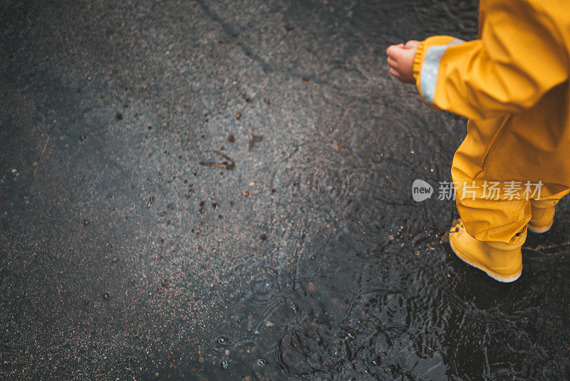 小男孩在雨中玩耍，跳进水里画画