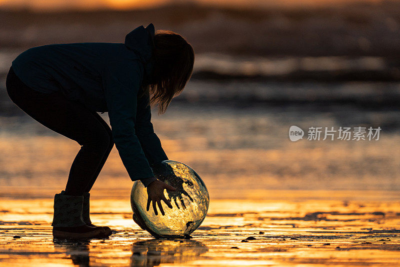 日出时，女人在海滩边拿着水晶球