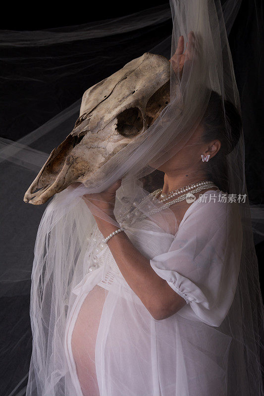 侧面的怀孕的加拿大土著妇女与牛头骨的脸。