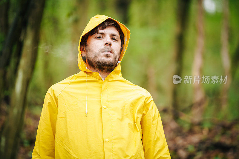 男人穿雨衣和吸烟的肖像