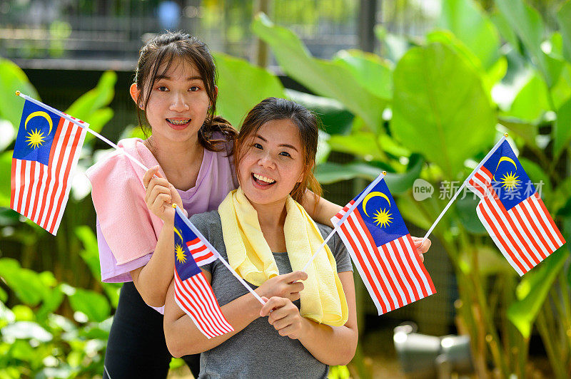 两名年轻女子在公园里挥舞着马来西亚国旗
