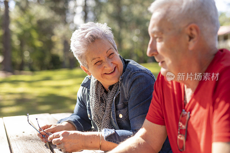 坐在公园长椅上的快乐老年夫妇