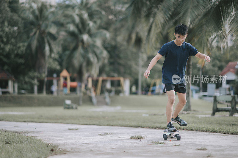 周末早上，一名亚裔中国少年在公园练习滑板和学习新技能