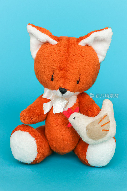 柔软的玩具姜狐狸与鸡在蓝色的背景。