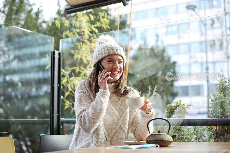 女孩坐在她最喜欢的café平台上，用手机和她的朋友聊天。