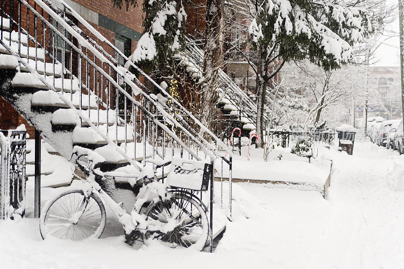 自行车被雪覆盖停在小城市的街道上